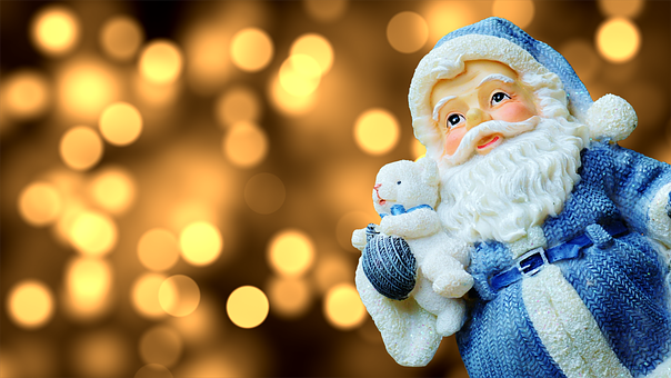 Mercatini di Natale - statua di Babbo Natale vestito di blu con luci di sottofondo