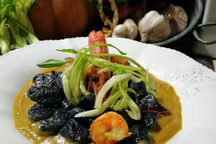 Black flour gnocchi with shrimp and crispy chicory - dish with black gnocchi and shrimp