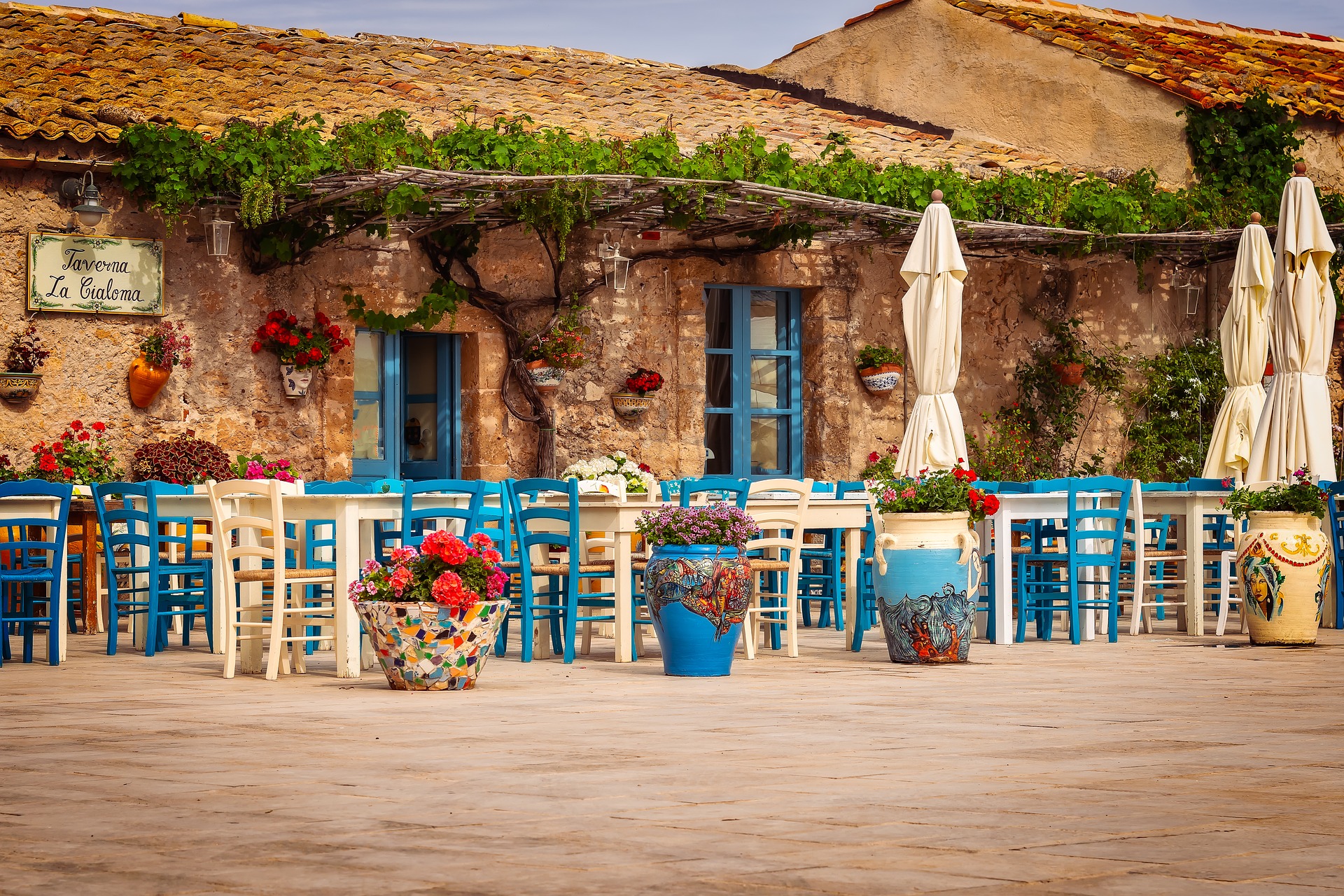 Cucina siciliana - Taverna caratteristica con tavoli e sedie bianchi e azzurri posti all'aperto