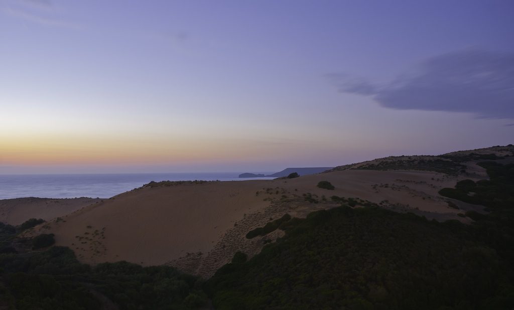Torre dei Corsari. Deserto al tramonto con dune di sabbia sotto il cielo con sfumature viola, gialle e arancioni