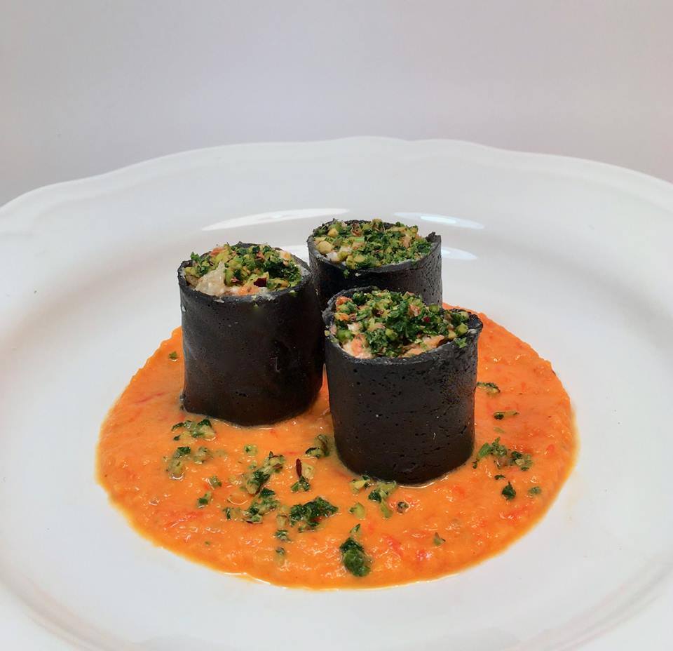 dish with sauce with the Crespelle inside in cuttlefish ink