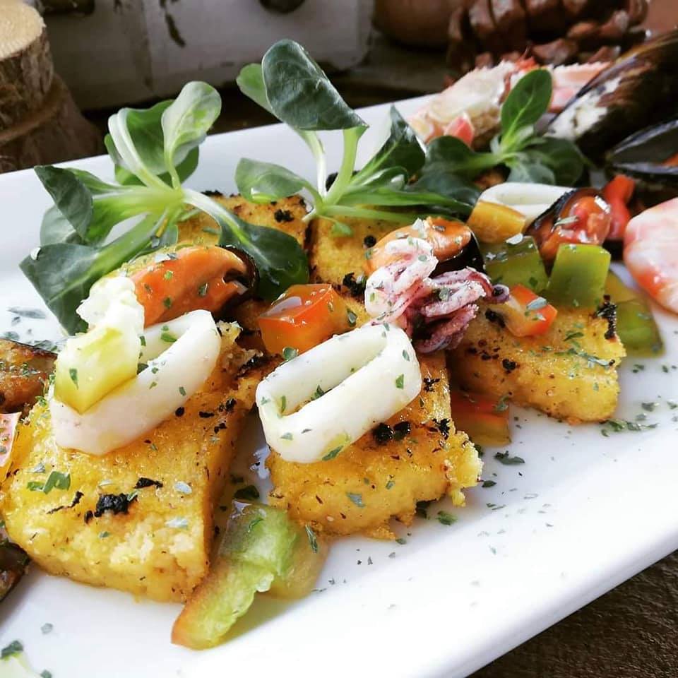 5 cereal polenta croutons with squid and mussels on a white plate