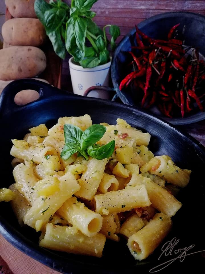 pot with bacon rigatoni and basil leaves