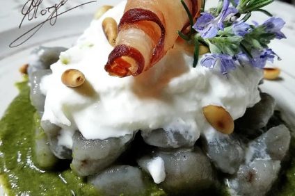 closeup of purple potato gnocchi with crispy bacon burrata and turnip greens cream on a plate