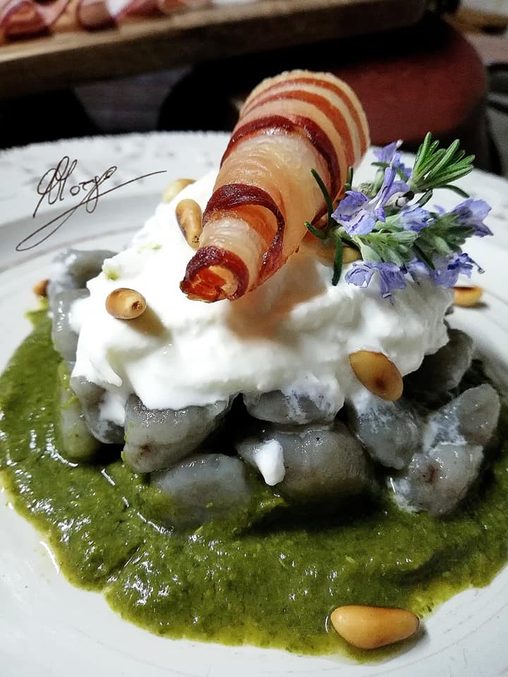 primo piano degli Gnocchi di patate viola con burrata bacon croccante e crema di cime di rapa in piatto