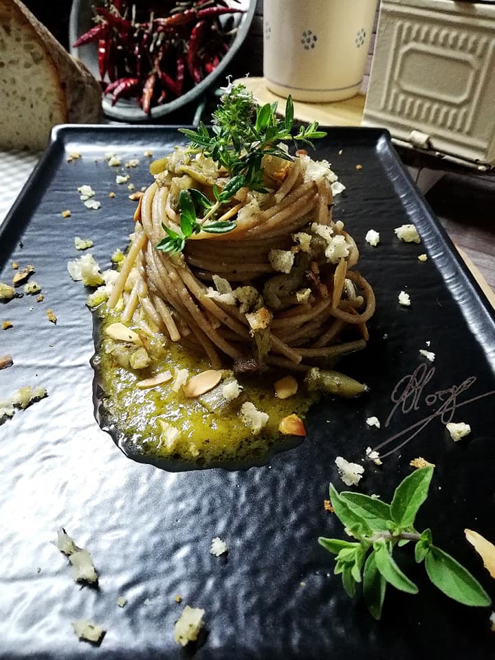 primo piano degli Spaghetti integrali con alici carciofi e mandorle tostate su salsa di datterini gialli 