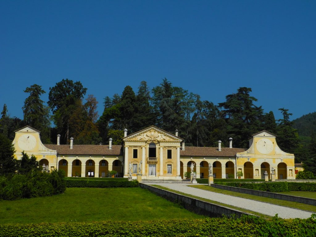 villa palladiana di colore bianco e giallo con prato verde davanti