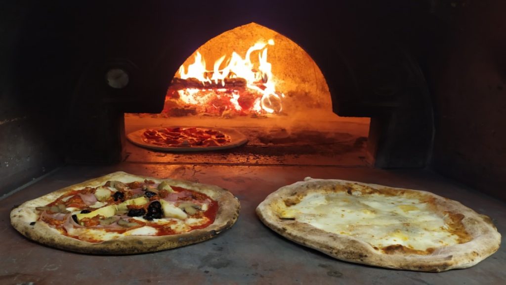 pizza - in the foreground two round pizzas in the wood oven