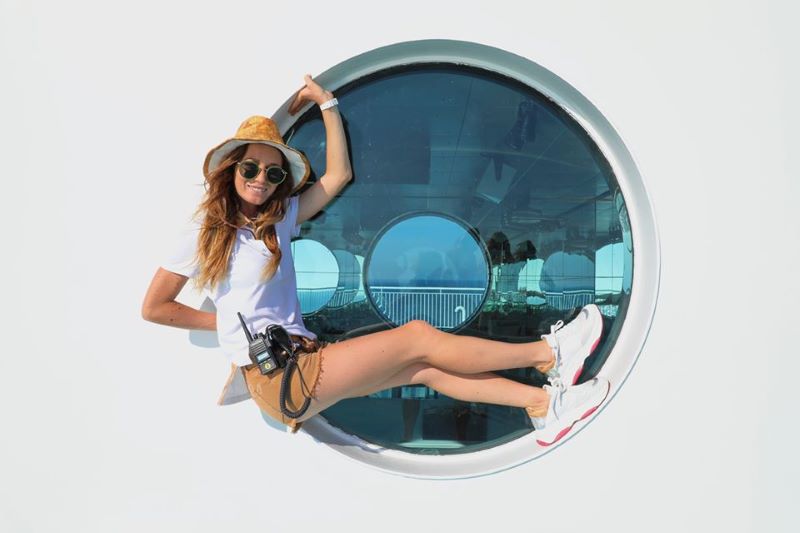 Mujer con sombrero posando para una foto dentro de la portilla de un barco