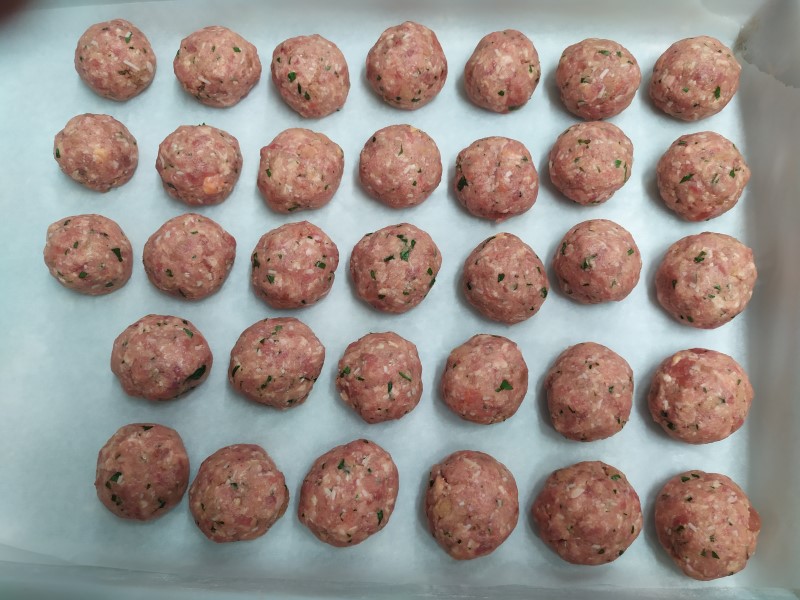 many raw meatballs on parchment paper