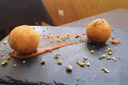 Arancini - due arancini su un piatto nero