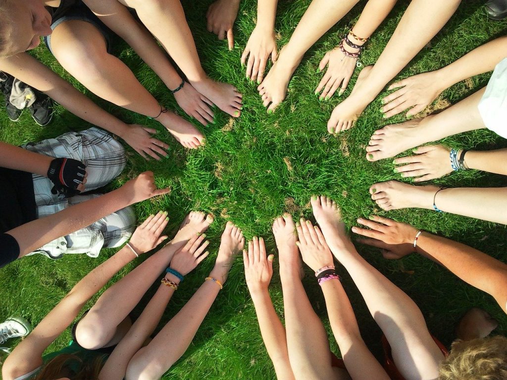 Esperienza tattile di mani e piedi nudi in un prato verde / green