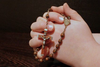 in prayer - a rosary in the hands