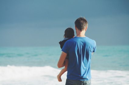 life - a man with a child in his arms by the sea