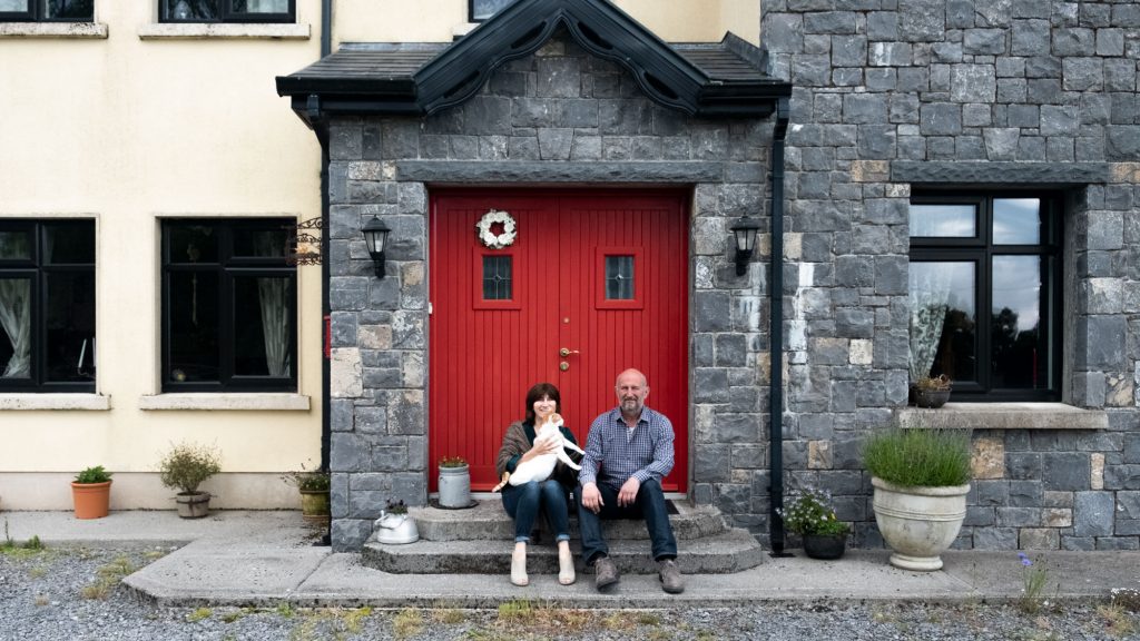 Attilio y Patrizia con el gato Gastone, sentados frente al B&B Casagastone