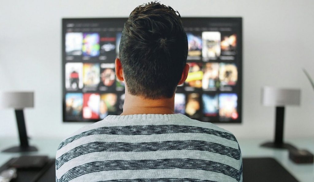 Movies to watch during curfew - Man watching Netflix catalog on TV
