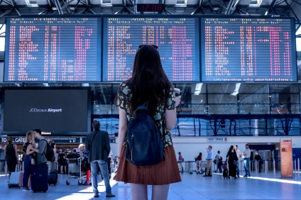 Passaporto sanitario digitale - ragazza guarda tabellone partenze in aeroporto