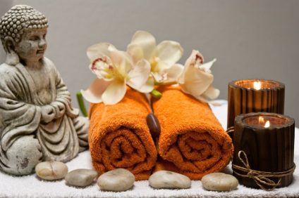 Spa bonus - two orange towels with a Buddha statue, flowers, stones and candles