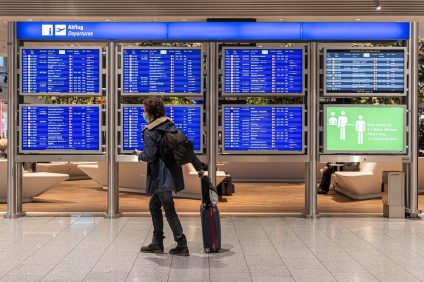 Restrictions for travel to Italy - traveler at the airport in front of the departures board