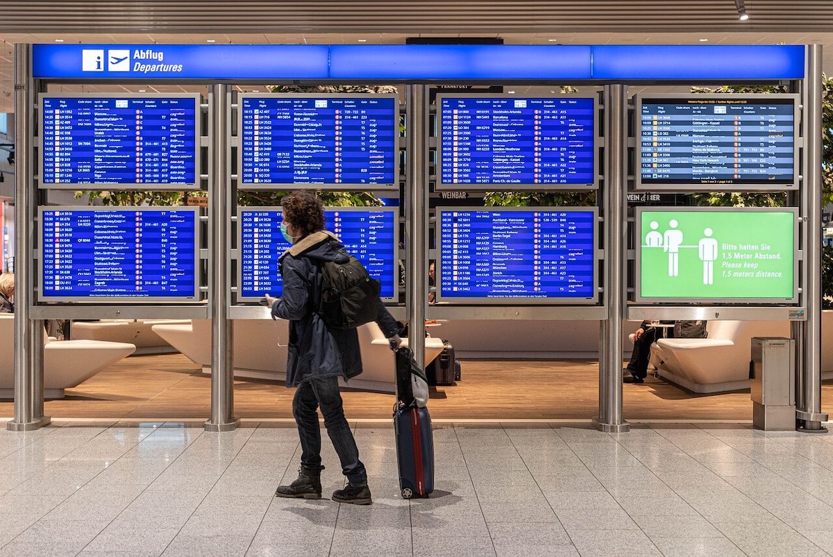 Restrizioni per i viaggi in Italia - viaggiatore in aeroporto davanti il tabellone della partenze