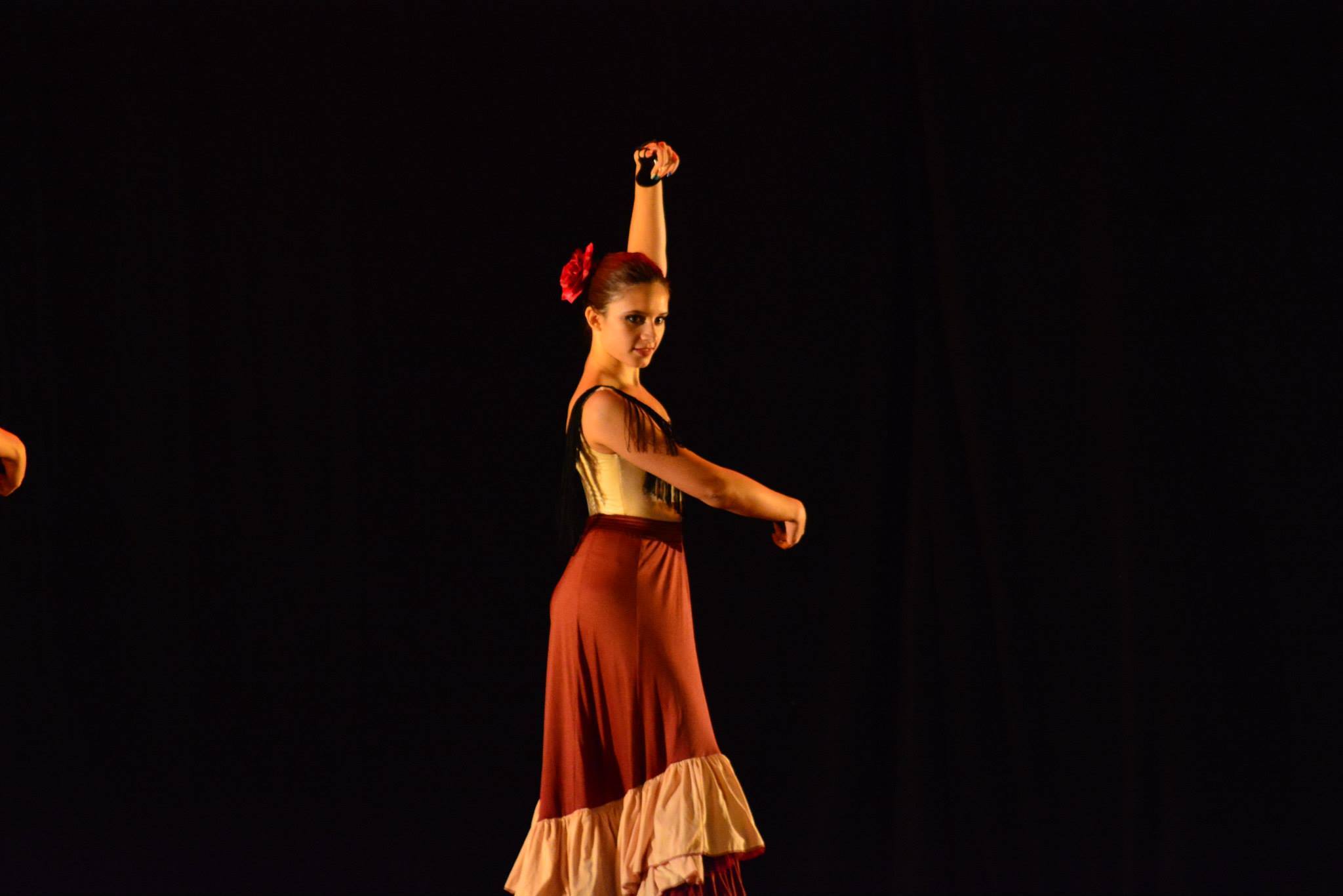 Giordana di Stefano che balla il tango, indossa un abito lungo bordeaux e un fiore rosso in testa