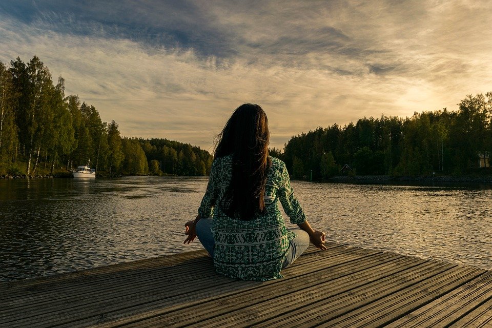 Una ragazza che medita in riva a un lago